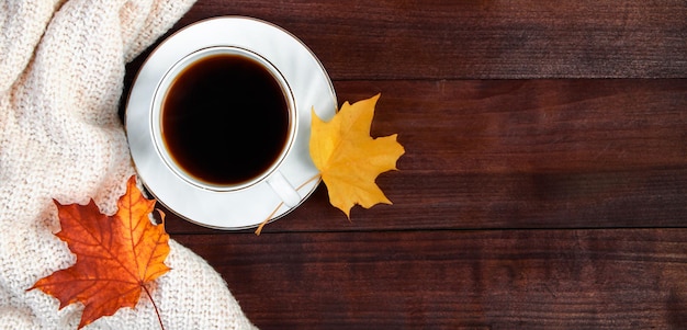 Kopje hete espressokoffie en gevallen gele bladeren op houten achtergrond Herfst ochtend concept