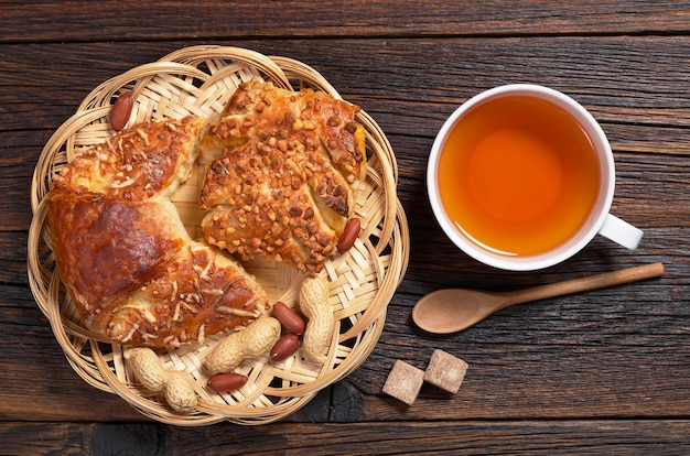 Kopje hete thee en verse broodjes met kaas en noten op rustieke houten tafel, bovenaanzicht