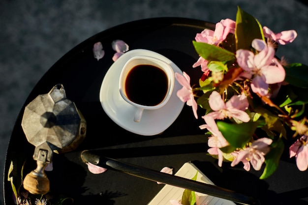 Kopje koffie bloemen en notitieboekje op de kleine zwarte tafel