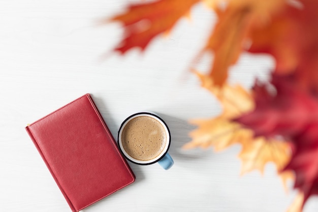 Kopje koffie boek en kleurrijke herfstbladeren op witte houten achtergrond bovenaanzicht. Herfst achtergrond