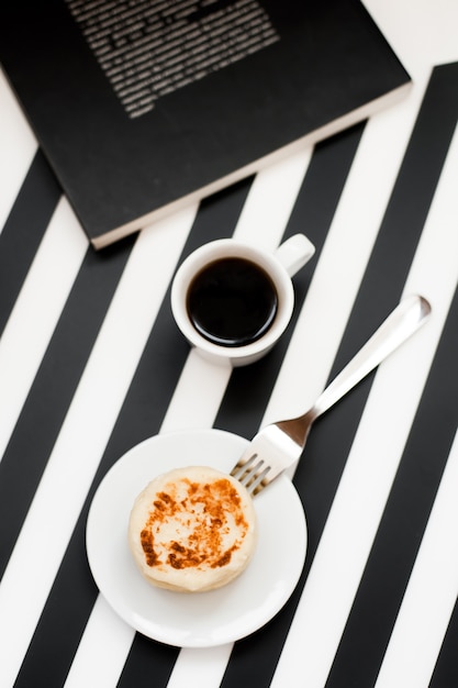 Kopje koffie en bakkerij op gestreepte zwart-witte achtergrond.