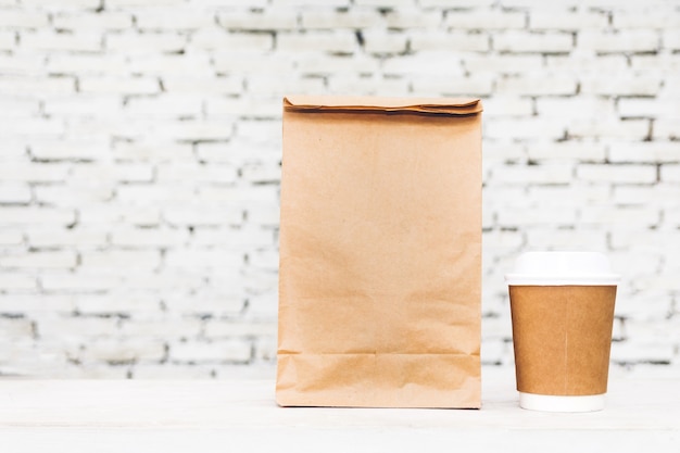 Kopje koffie en blanco papieren zak met kopie ruimte voor uw merk op tafel