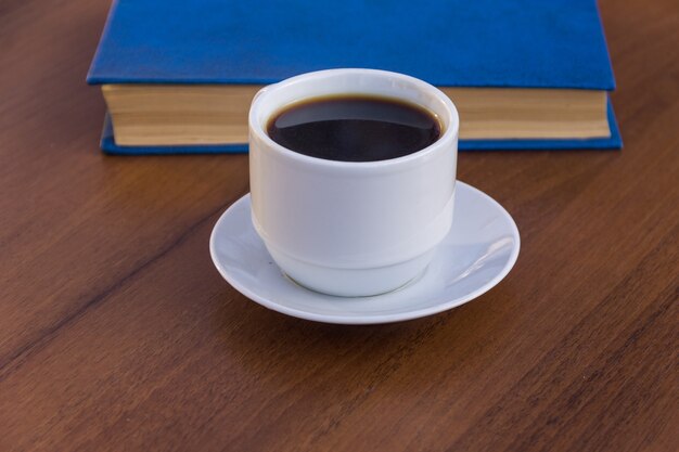 Kopje koffie en boek op houten tafel