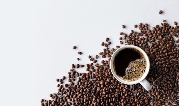 Kopje koffie en bonen op witte tafel achtergrond. bovenaanzicht