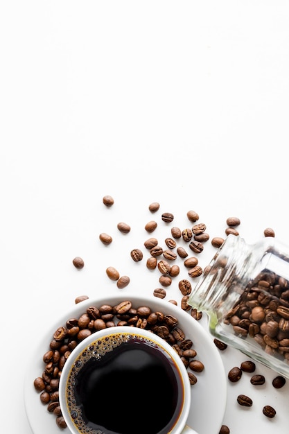 Kopje koffie en bonen op witte tafel achtergrond bovenaanzicht