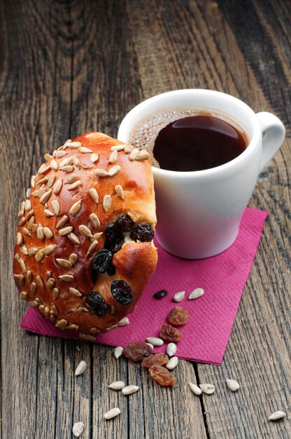 Kopje koffie en broodjes met zonnebloempitten en rozijnen op houten tafel