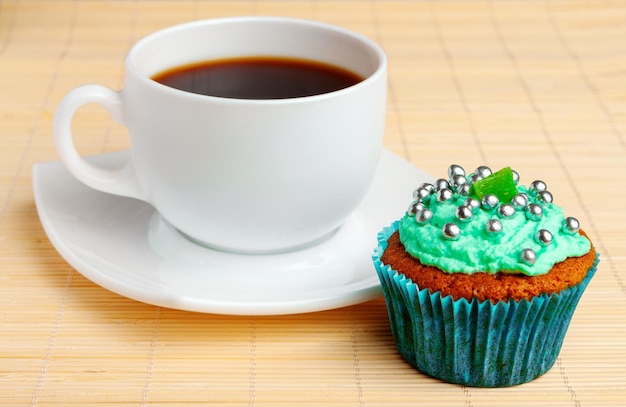 Kopje koffie en cupcake met slagroom en decoratieve kralen