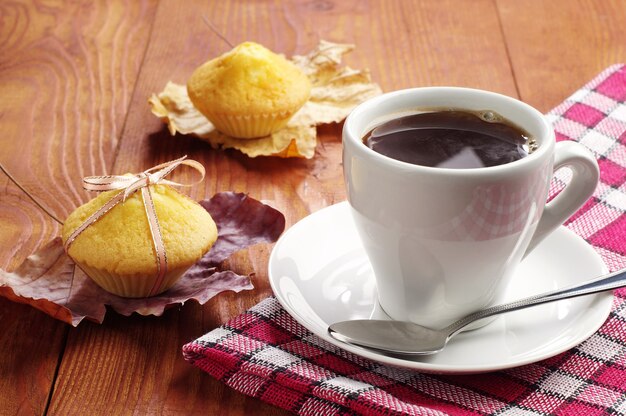 Kopje koffie en cupcakes op houten tafel