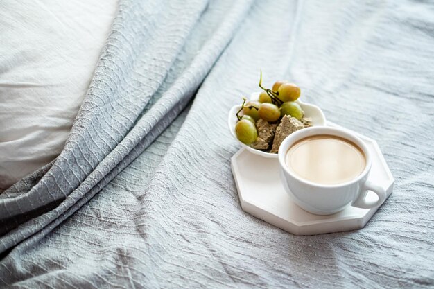 Kopje koffie en druiven met gezellig kussen op deken in het interieur van de slaapkamer