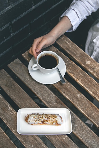 Kopje koffie en eclair op een houten tafel close-up