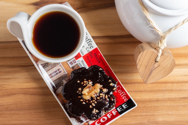 Kopje koffie en een chocolade snoepje onder de houten tafel