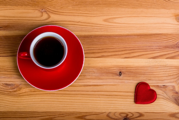Foto kopje koffie en een hart op houten achtergrond. bovenaanzicht. vrije kopie ruimte