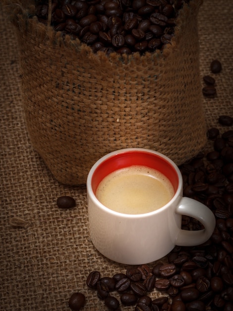 Kopje koffie en gebrande koffiebonen in een canvas zak op jute