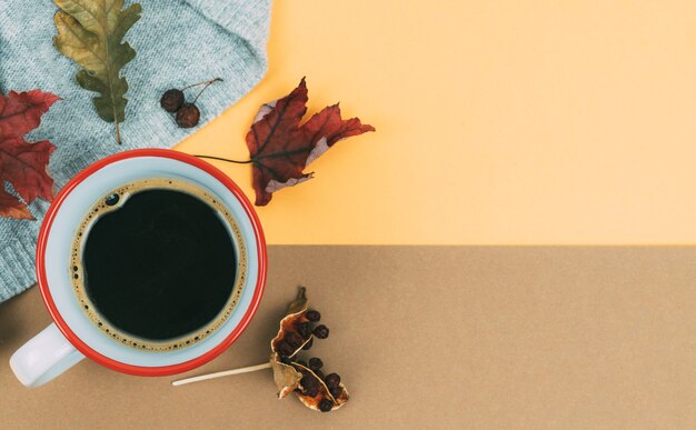 Kopje koffie en gedroogde bladeren op een oranje en bruine achtergrond. Herfst concept.