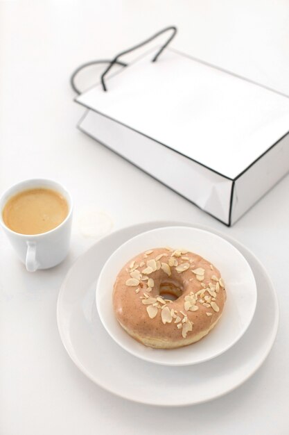 Kopje koffie en geglazuurde donut met zak