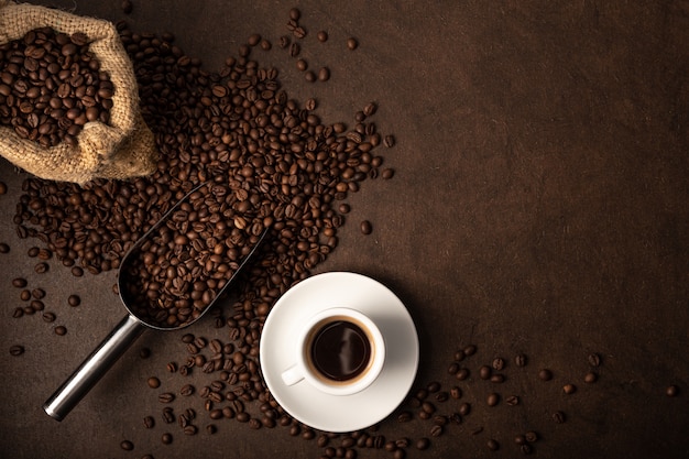 Kopje koffie en lepel op bruine achtergrond. Bovenaanzicht kopie ruimte