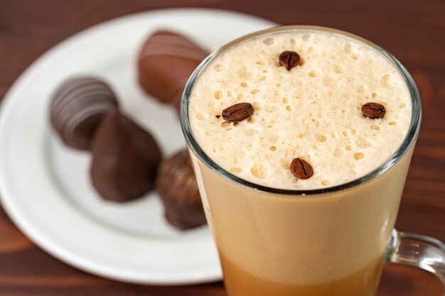 Kopje koffie en schotel met chocoladesnoepjes op houten tafel close-up