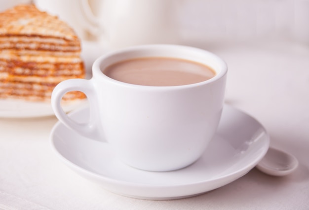 Kopje koffie en stuk wafel cake op de witte tafel.