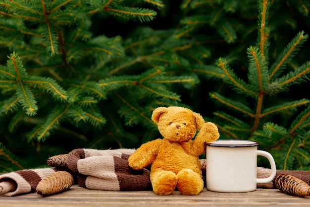 Kopje koffie en teddybeer op houten tafel met vuren takken op achtergrond