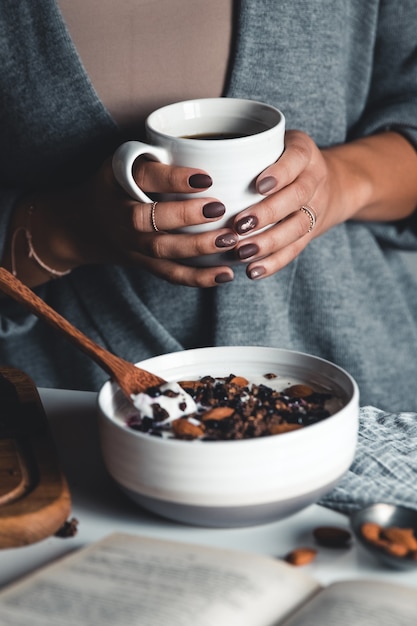 Kopje koffie in handen. Het meisje is aan het ontbijten. mooie manicure. Gezond ontbijt. Smoothie Bowl