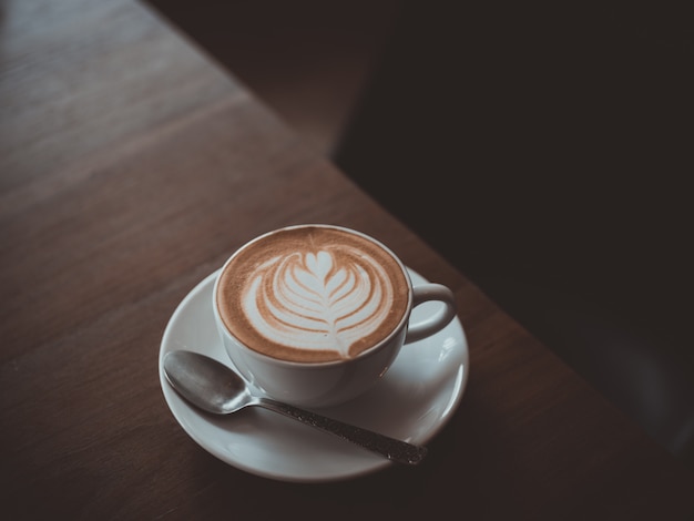 kopje koffie latte kunst op de houten bureau coffeeshop café