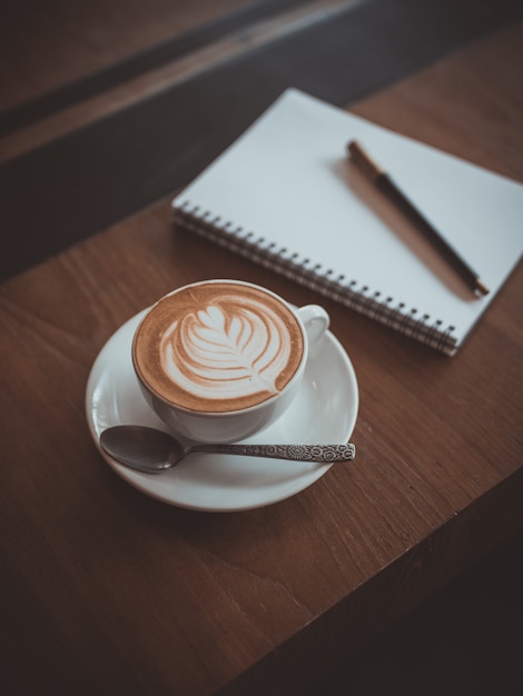 kopje koffie latte kunst op de houten bureau coffeeshop café