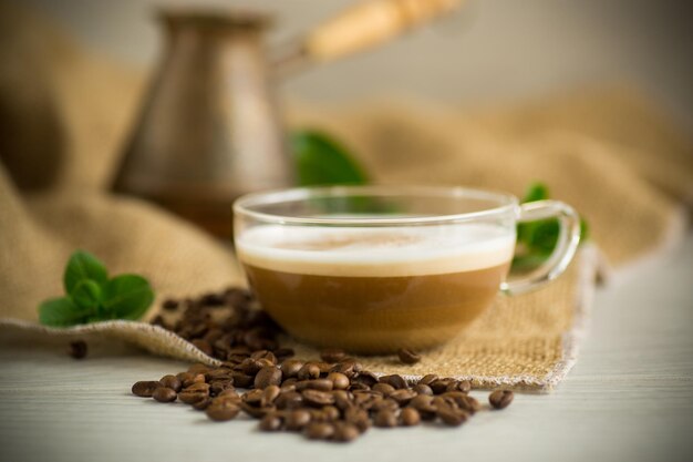 Kopje koffie latte met hart vorm en koffiebonen op oude houten achtergrond