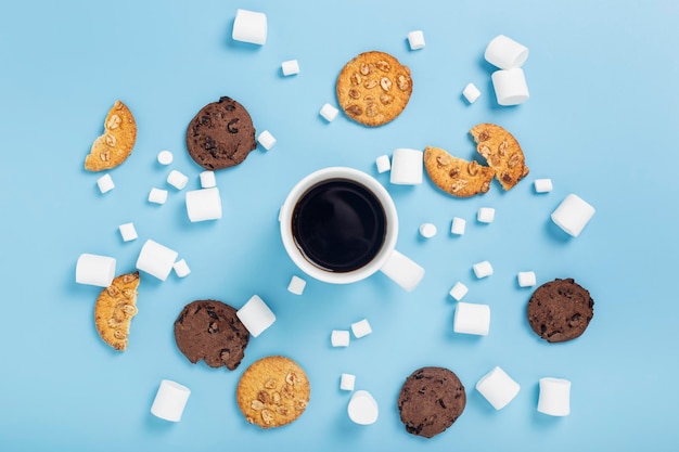 Kopje koffie, marshmallow, koekjes op een blauwe achtergrond. Bovenaanzicht, plat gelegd.