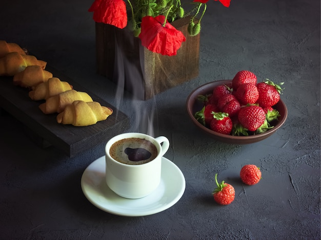 kopje koffie met aardbeien en croissants op een houten dienblad