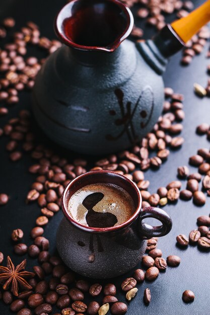 Kopje koffie met cezve met een verstrooiing van koffiebonen op een donker