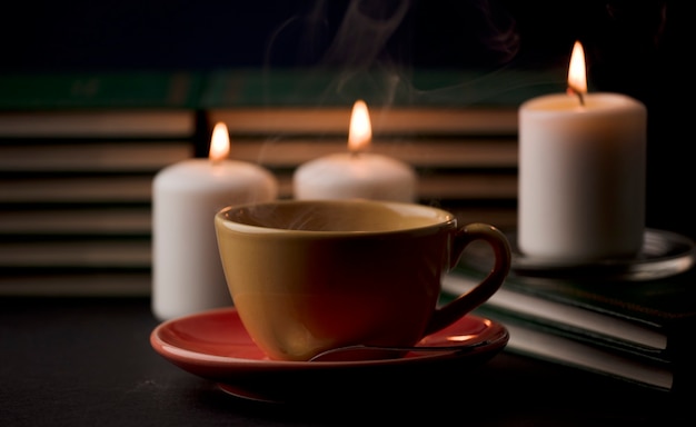 kopje koffie met hete rook en drie brandende kaarsen op het bureau thuis stroomstoring