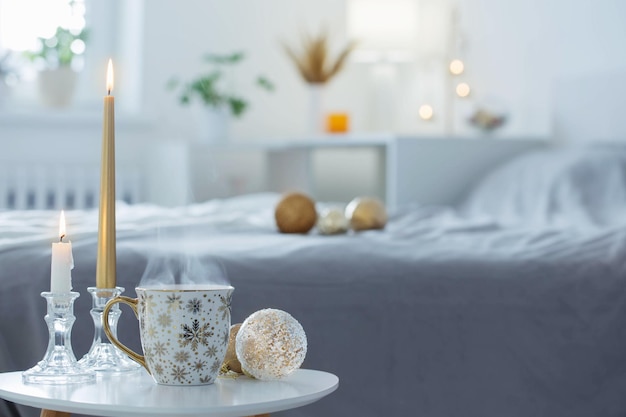 Kopje koffie met kerstballen op tafeltje in witte slaapkamer
