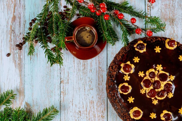 Kopje koffie met koffiebonen en cake, pijnboomtak met rode bessen.