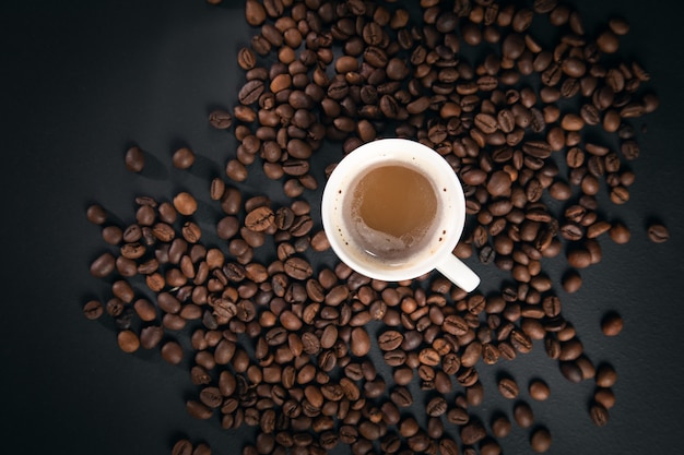 Kopje koffie met koffiebonen op de zwarte achtergrond