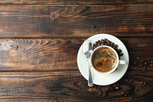 Kopje koffie met lepel en koffiebonen op houten achtergrond