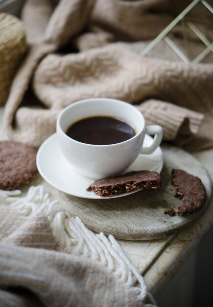 Kopje koffie met melk en chocoladekoekjes op warme wollen deken