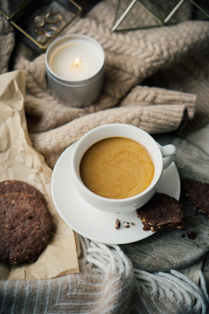 Kopje koffie met melk en chocoladekoekjes op warme wollen deken