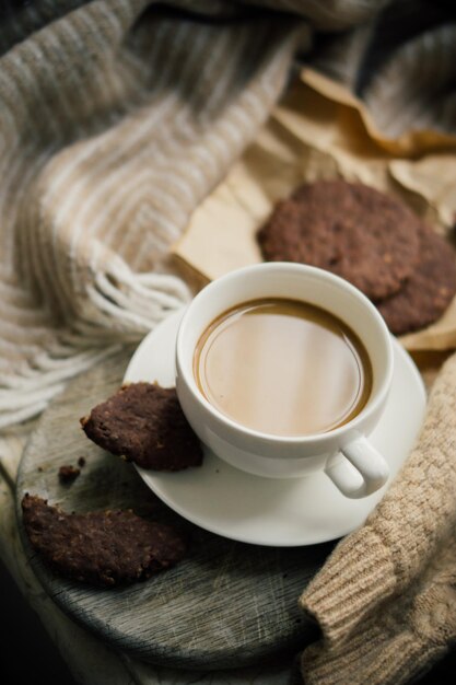 Kopje koffie met melk en chocoladekoekjes op warme wollen deken