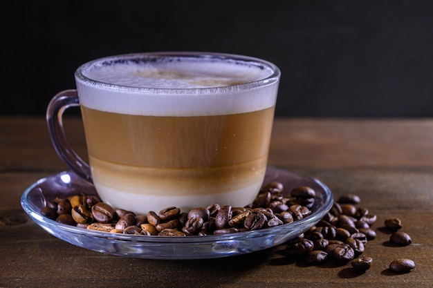 Kopje koffie met melk op een donkere achtergrond Hete latte of cappuccino bereid met melk op een houten tafel