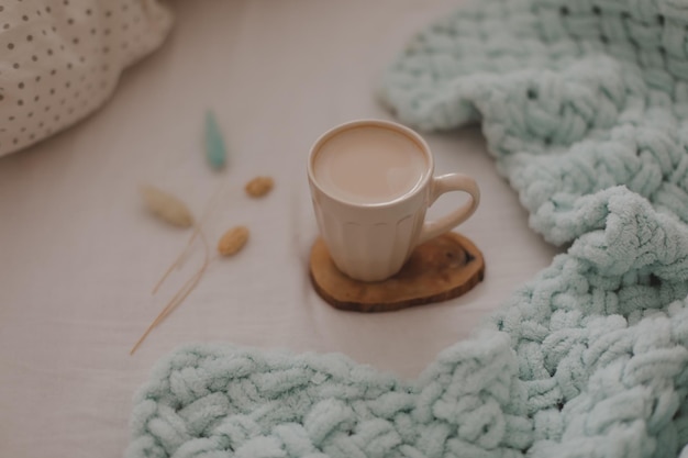 Kopje koffie met melk op het bed met wit beddengoed en deken Ochtendkoffie in bed concept