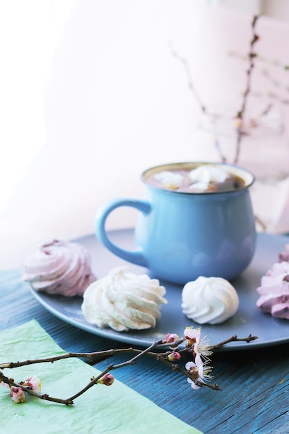 Kopje koffie met meringue bloeiende kersentakken in water in een glazen pot zoet dessert