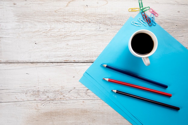 Kopje koffie met potloden op blauw papier op tafel