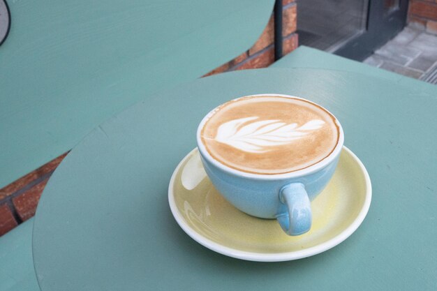 Kopje koffie met prachtige latte art op turquoise tafel voor tekst Foto van hoge kwaliteit