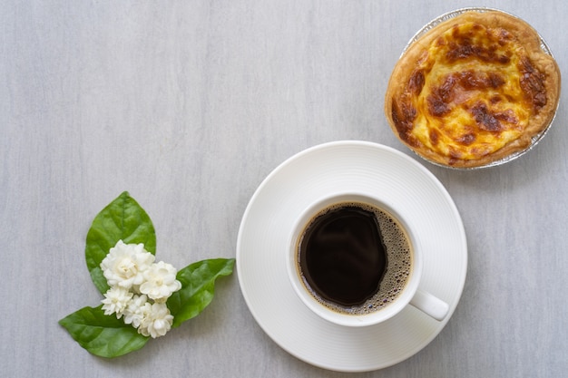 Kopje koffie met quiche op witte tafel.