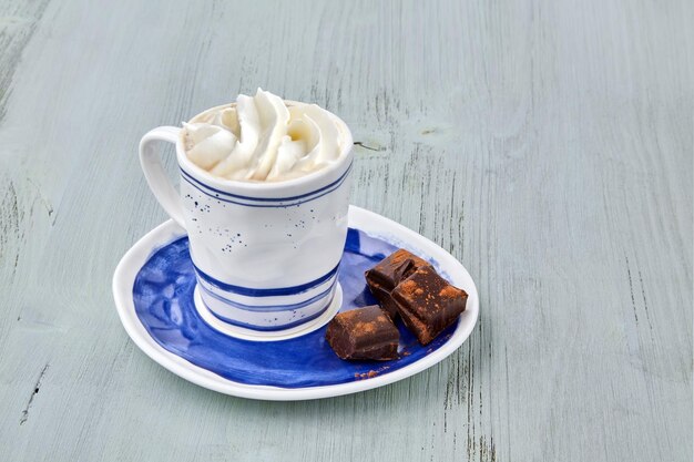 Kopje koffie met slagroom en gehakte chocolade op een lichtblauwe houten tafel Drankjes op basis van koffie Koffiedag