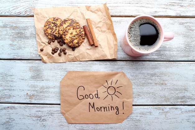 Kopje koffie met verse koekjes en Have A Nice Day massage op houten tafelblad bekijken