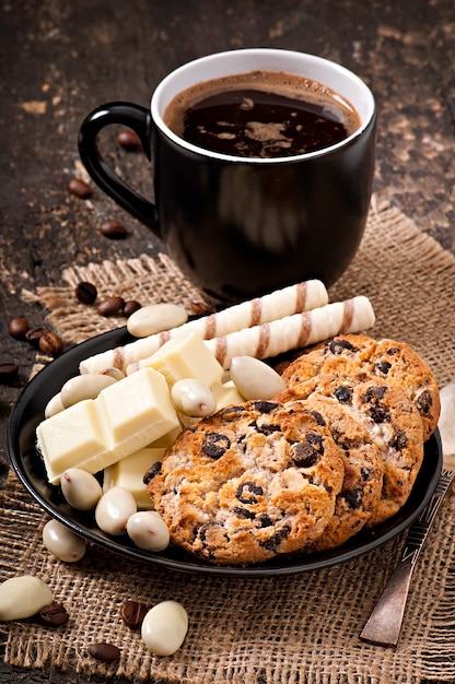 Kopje koffie met witte chocolade, amandelen en koekjes