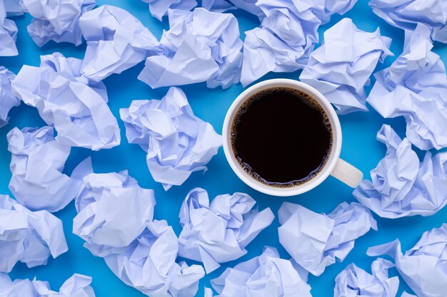 Kopje koffie met witte verfrommeld papier ballen