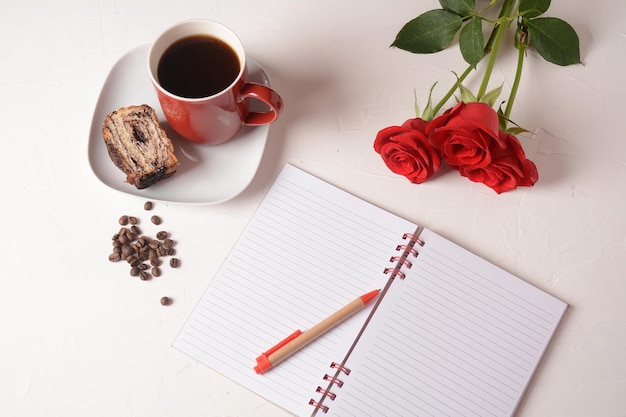 Kopje koffie notebook pen en roze bloemen Koffiepauze in de ochtend