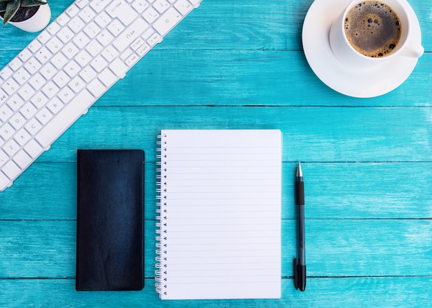 Kopje koffie, notebooks, pen op turquoise houten bureau